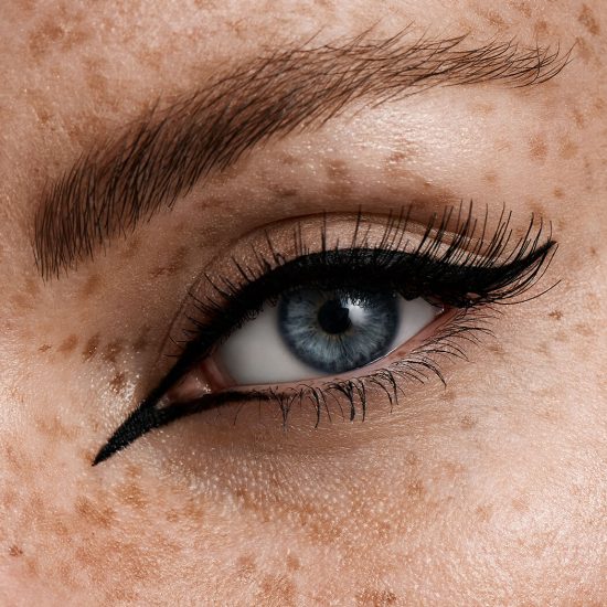blaues Auge mit schwarzem Eyeliner, langen Wimpern und Sommersprossen
