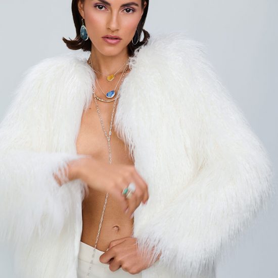 Fashionfotografie Frau mit weißer Pelz Jacke und weißer Hose in Bewegung mit schmuck um den Hals